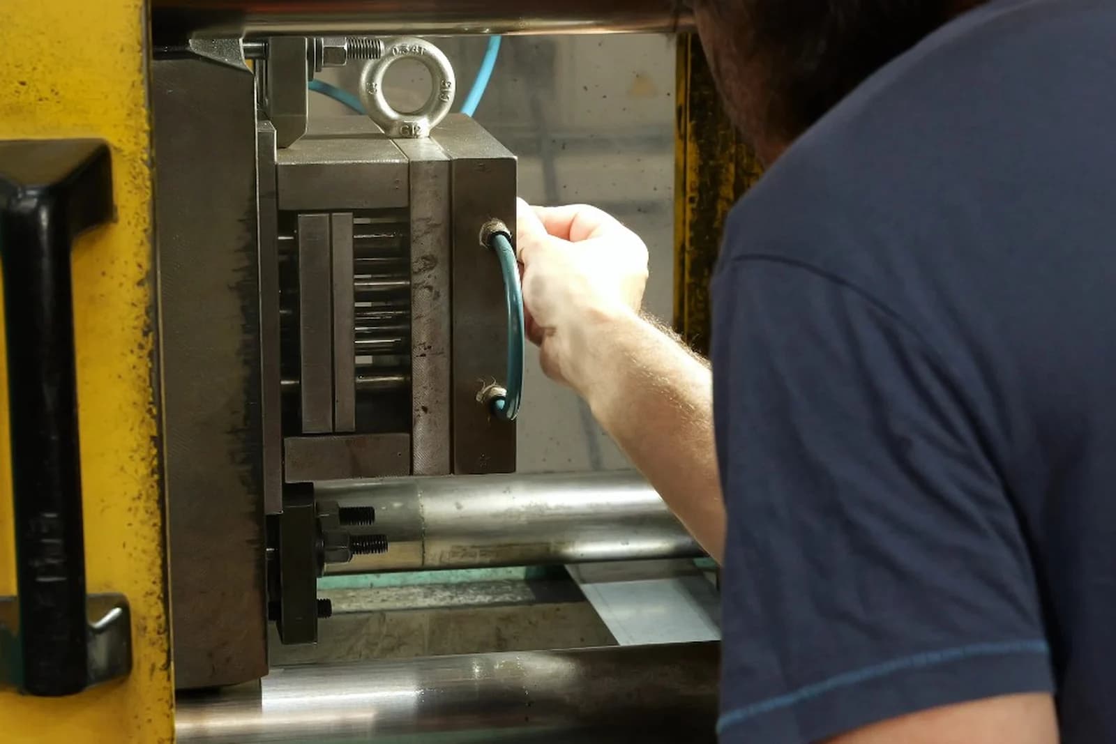 Operator adjusting a mold on industrial manufacturing machinery.