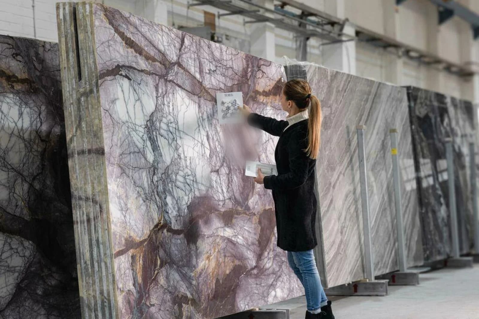 Professional inspecting a natural stone slab in a warehouse.