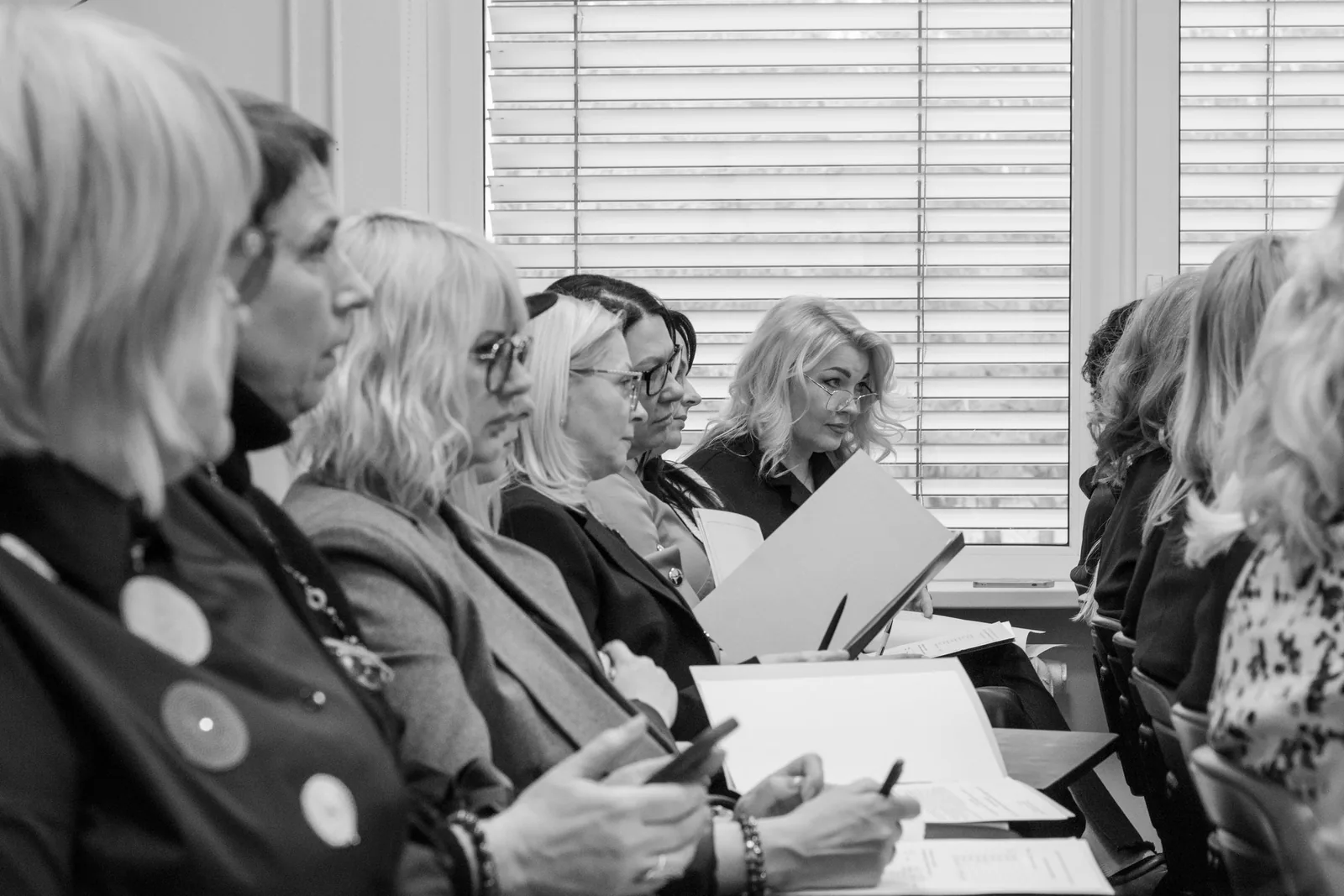 Adult women taking notes during a meeting or training session.